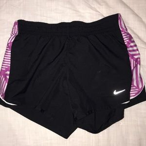 Black Nike shorts with purple and white accents.